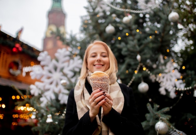 Schöne blondine mit spuckenkuchen am weihnachtsmarkt in breslau, polen