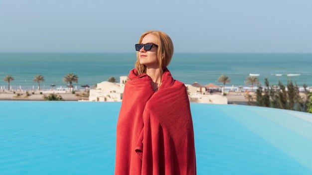 Schöne Blondine nach dem Schwimmen im Pool in ein rotes Handtuch gehüllt