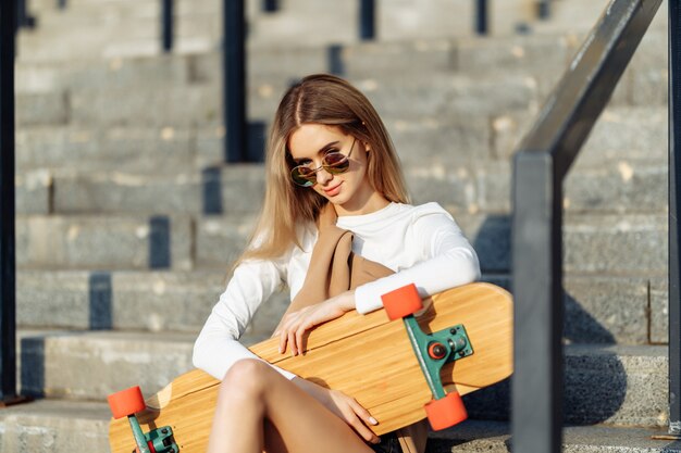 Schöne Blondine ruht sich nach dem Skateboarden aus. Hochwertiges Foto