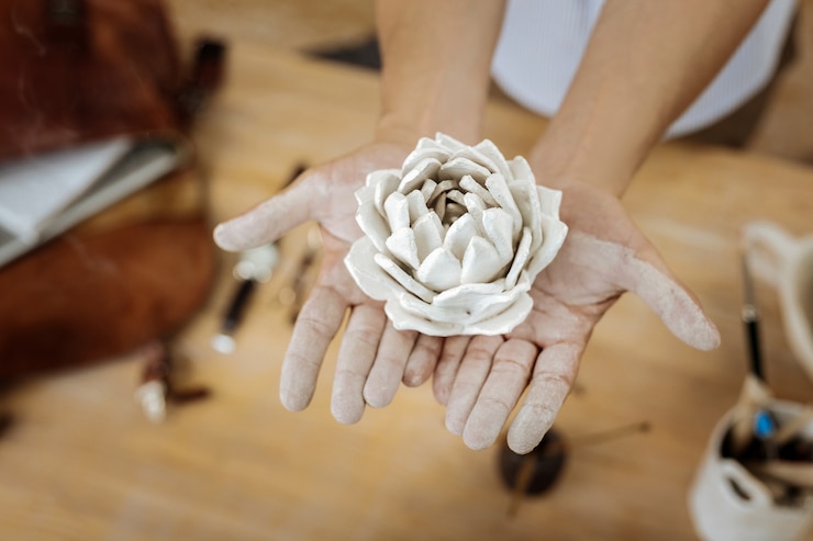 Foto schöne blume. schöne dekorative blume aus steingut in händen eines kreativ inspirierten handwerkers