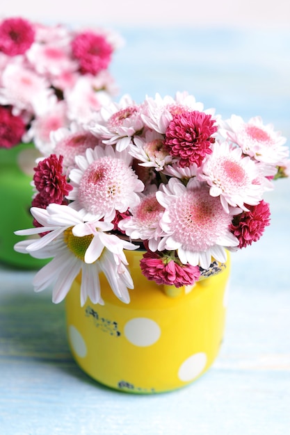 Schöne Blumen in Dosen auf Tisch auf heller Oberfläche