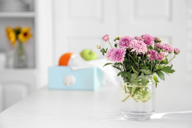 Schöne Blumen in Vase auf dem Tisch auf hellem Hintergrund