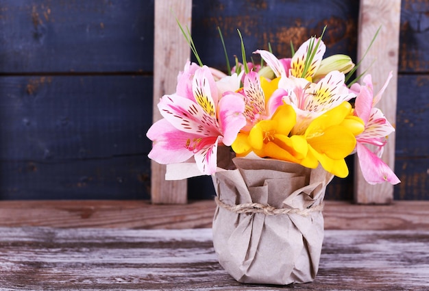 Schöne Blumen in Vase auf Holzuntergrund