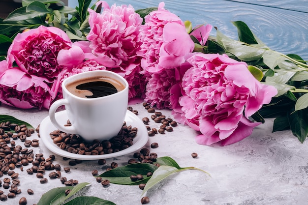 Schöne Blumenpfingstrosen nahe bei einem Tasse Kaffee
