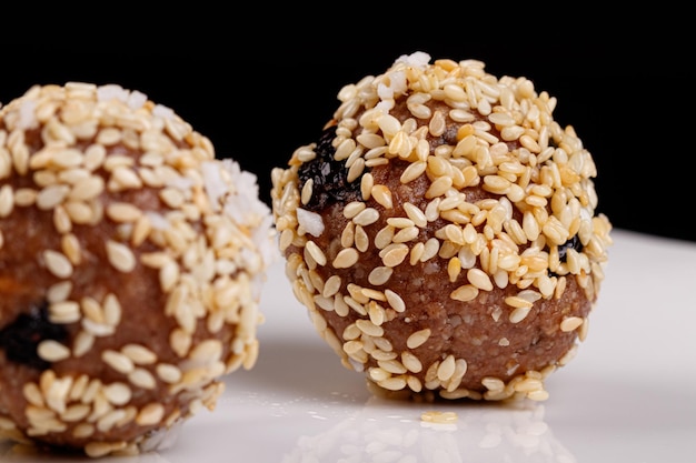 Schöne Bonbons mit Sesamsamen auf einem weißen Teller auf schwarzem Hintergrund