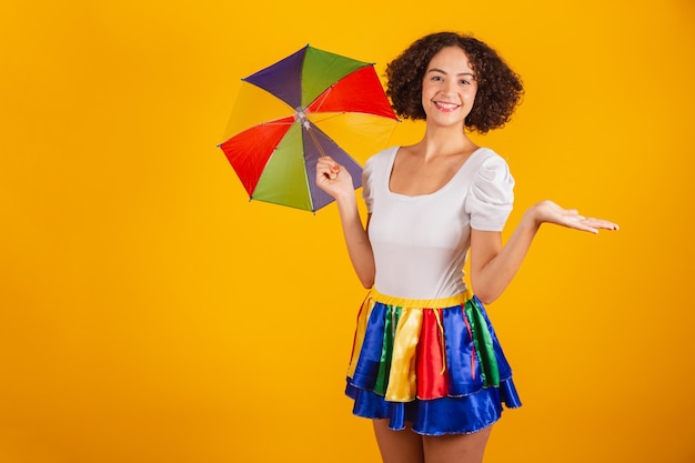 Schöne Brasilianerin in Karnevalskleidung, buntem Rock und weißem Hemd, Frevo-Regenschirm, sei willkommen