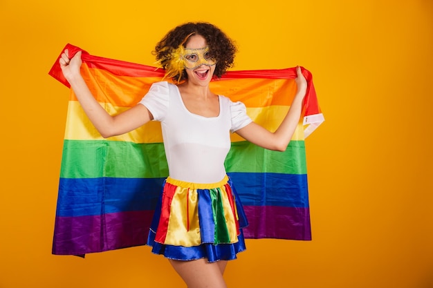 Schöne Brasilianerin in Karnevalskleidung, buntem Rock und weißem Hemd mit Wimperntusche mit LGBT-Flagge