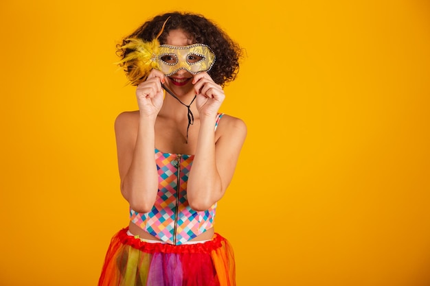 Schöne Brasilianerin in Karnevalskleidung, die eine Maske aufsetzt