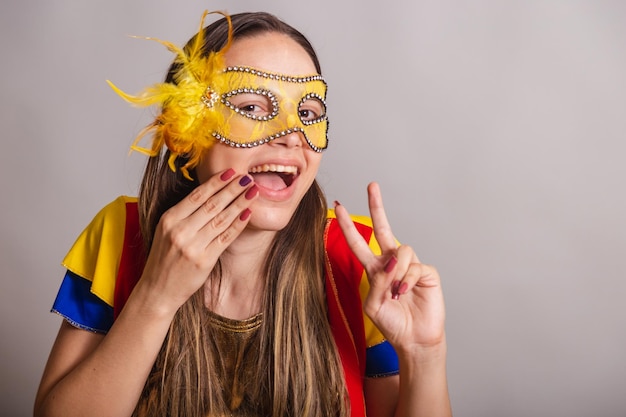 Schöne brasilianische kaukasische Frau, die Frevo-Karnevalskleidung trägt, die einen Maskenfrieden und eine Liebe trägt