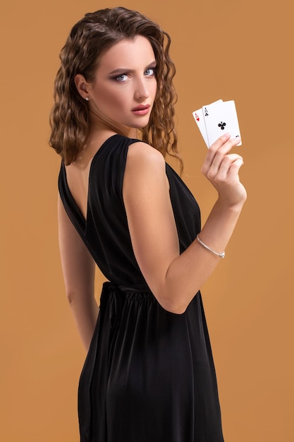 Schöne braunhaarige Frau mit zwei Assen als Zeichen für Pokerspiel, Glücksspiel und Casino