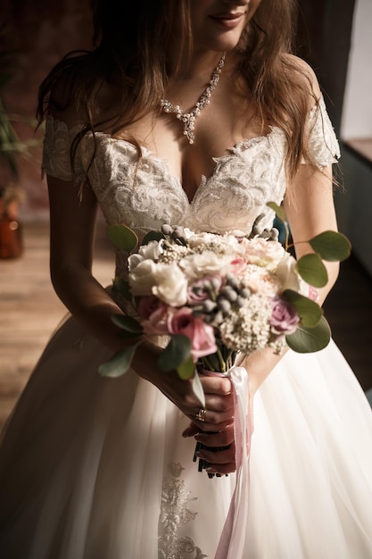 Schöne Braut, die an einem Hochzeitstag einen zarten Blumenstrauß in den Händen hält