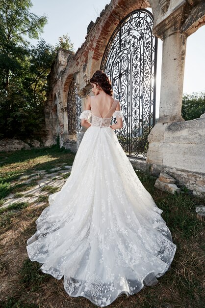 Schöne Braut im Hochzeitskleid, das am Hochzeitstag nahe dem alten Schloss fotografiert wird.