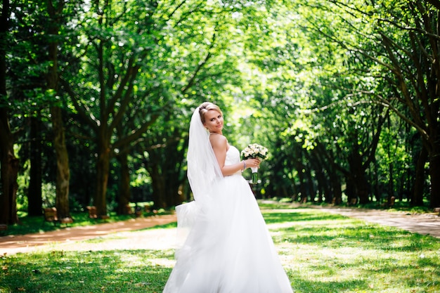 Schöne Braut im Modehochzeitskleid auf natürlichem Hintergrund. Die atemberaubende junge Braut ist unglaublich glücklich. Hochzeitstag. Ein schönes Brautporträt im Wald.