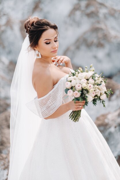 Schöne Braut in einem Hochzeitskleid mit einem Blumenstrauß auf der Spitze der Salzberge. Eine atemberaubende junge Braut mit lockigem Haar. Hochzeitstag. . Schönes Porträt der Braut ohne den Bräutigam.