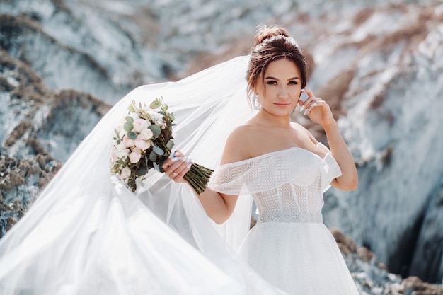 Schöne Braut in einem Hochzeitskleid mit einem Blumenstrauß auf der Spitze der Salzberge