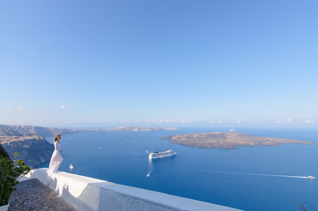 Schöne Braut In einem weißen Kleid, das vor dem Hintergrund des Mittelmeers in Thira, Santorini aufwirft.