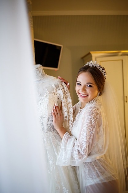 Schöne Braut kleidet ihr weißes Hochzeitskleid