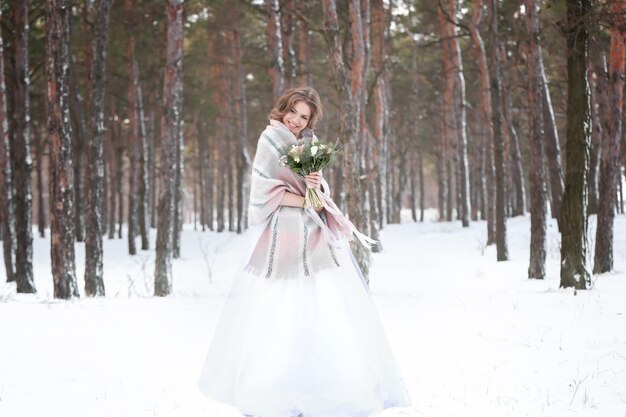 Schöne Braut mit Blumenstrauß draußen am Wintertag