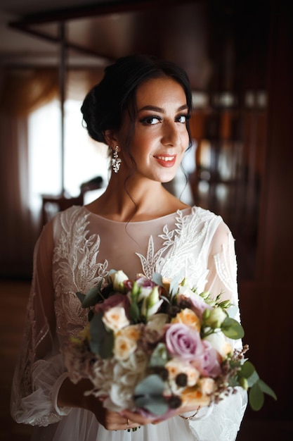 Schöne Braut mit einem Hochzeitsblumenstrauß Hübsche Frau mit professionellem Make-up und Frisur Hochzeitstag