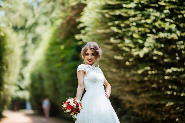 Schöne Braut mit einem Hochzeitsstrauß in ihren Händen draußen im Park