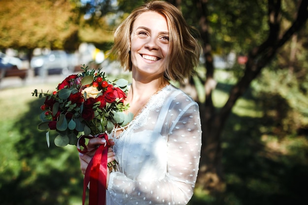 Schöne Braut mit Hochzeitsblumenstrauß im Park Elegante Frau mit professionellem Make-up und Frisur