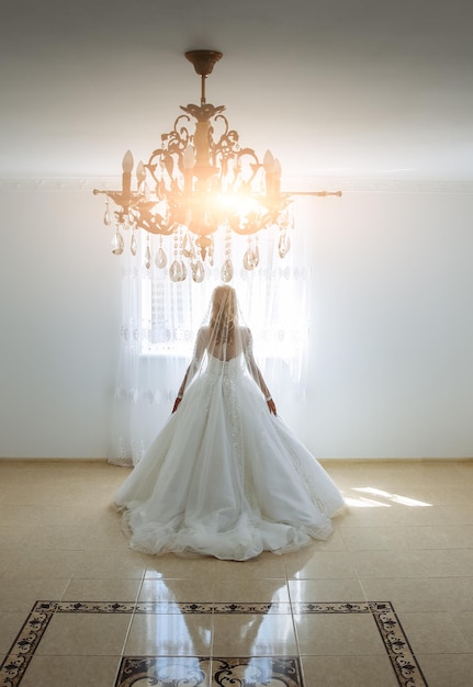 Schöne Braut mit Spitzenschleier geht in den Raum Hochzeitsfoto Luxuswohnung