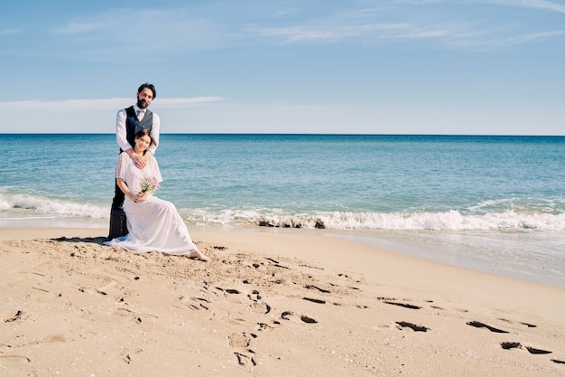 Schöne Braut und Bräutigam am Strand schauen sich mit viel Liebe und Freude an