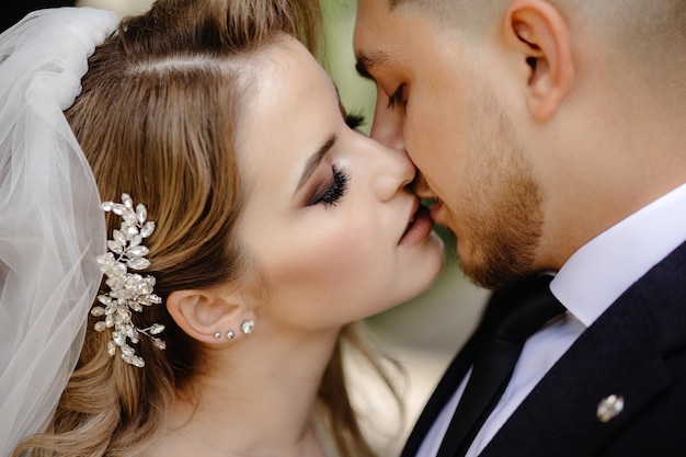 Schöne Braut und Bräutigam, die an ihrem Hochzeitstag im Freien umarmen und küssen