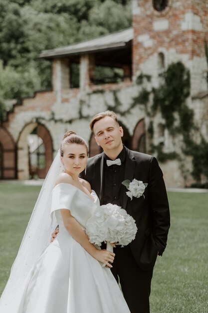 Schöne Braut und Bräutigam, die an ihrem Hochzeitstag im Freien umarmen und küssen