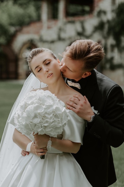 Schöne Braut und Bräutigam, die an ihrem Hochzeitstag im Freien umarmen und küssen