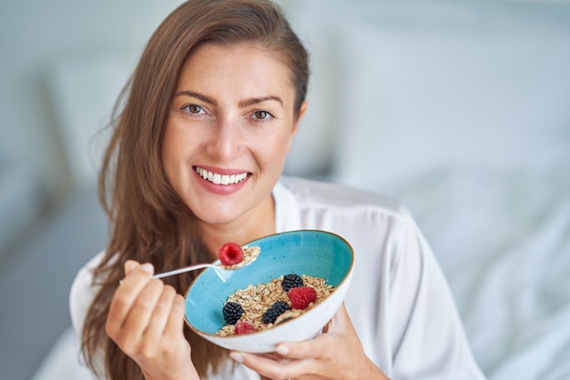 Foto schöne brünette auf dem bett mit müslifrühstück