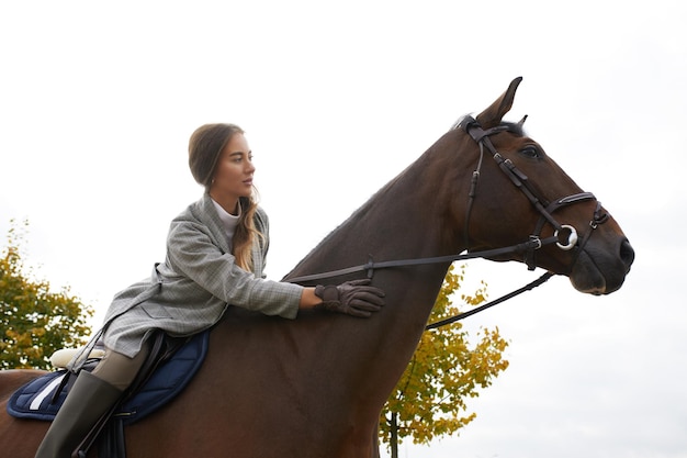 Schöne Brünette auf einem Pferd auf dem Hintergrund einer Landschaft im Herbst Reiten aktives Reiten