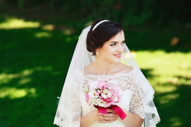 Schöne brünette Braut mit Blumenstrauß im Freien