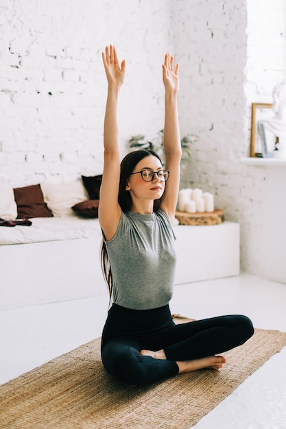 Schöne brünette Fitnessfrau meditieren, Yoga drinnen zu Hause zu tun