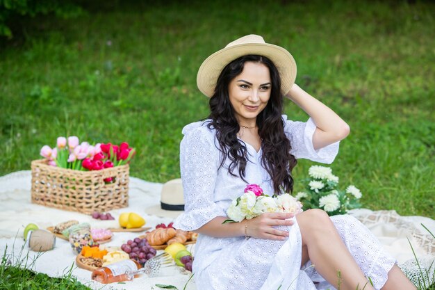 schöne brünette Frau, die im Park auf einer Picknickdecke sitzt und sich in der Natur ausruht