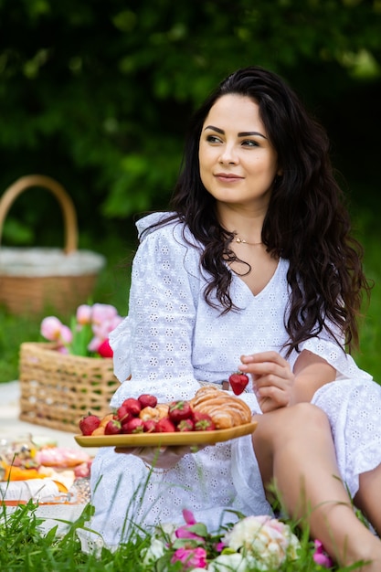 schöne brünette Frau, die im Park auf einer Picknickdecke sitzt und sich in der Natur ausruht