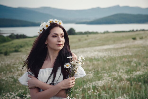 Schöne brünette Frau genießt den Frühling auf einem Feld von Gänseblümchen