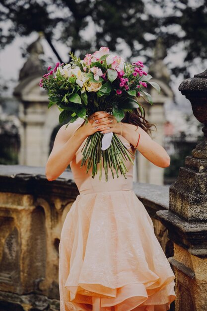 Schöne brünette Frau mit einem Blumenstrauß in einem rosa Kleid