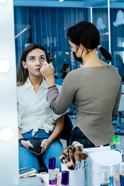 Schöne brünette Frau wird in einem Schönheitssalon mit einem Pinsel abgestaubt und getönt