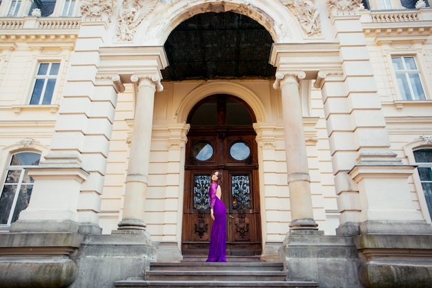 Schöne brünette junge Frau, die modisches lila Kleid trägt