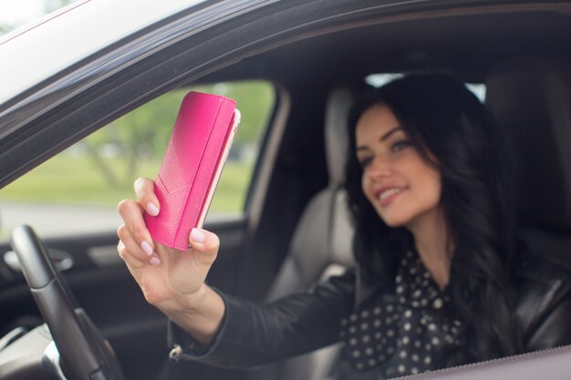 Schöne Brunettefrau, die selfie im Auto tut