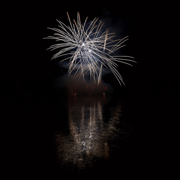 Schöne bunte Feuerwerk auf der Wasseroberfläche mit einem sauberen schwarzen Hintergrund. Fun Festival und internationaler Wettbewerb von Feuerwehrleuten aus aller Welt Ignis Brunensis 2017. Brno Dam - Tschechische Republik.