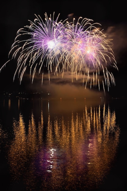 Schöne bunte Feuerwerk auf der Wasseroberfläche mit einem sauberen schwarzen Hintergrund. Fun Festival und internationaler Wettbewerb von Feuerwehrleuten aus aller Welt Ignis Brunensis 2017. Brno Dam - Tschechische Republik.