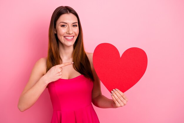 Schöne Dame, die gegen die rosa Wand mit rotem Herzen aufwirft