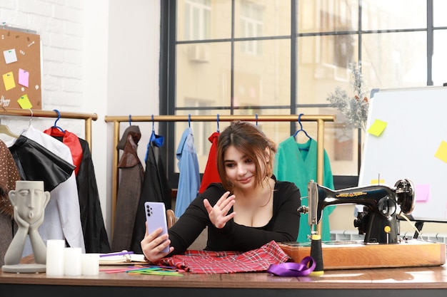 Schöne Dame, die im Atelier sitzt und auf ihr Telefon schaut