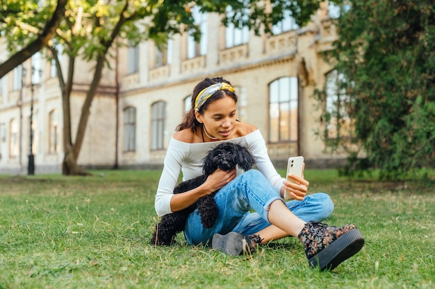 Schöne Dame, die Selfie auf dem Smartphone mit Hunderasse-Zwergpudel macht