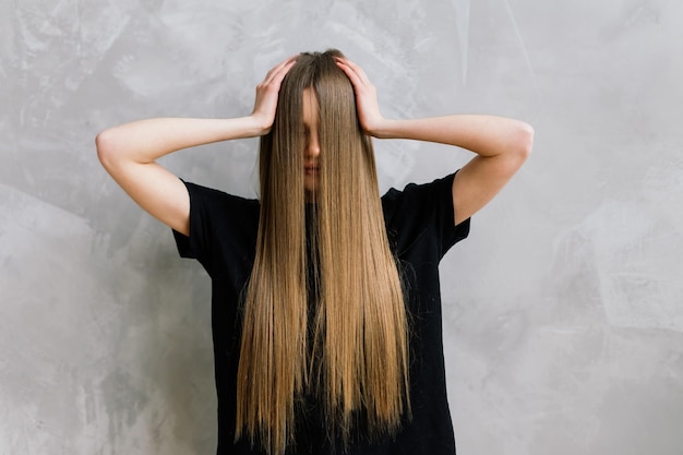 Schöne Dame macht ihr Make-up und Haare im Schlafzimmer. Attraktive junge Frau mit ziemlich langen Haaren