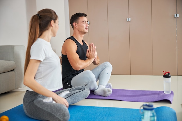 Schöne Dame und ihr Freund beim Yoga zu Hause