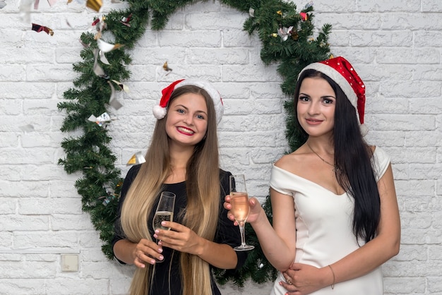 Schöne Damen mit Champagner und Weihnachtsmützen