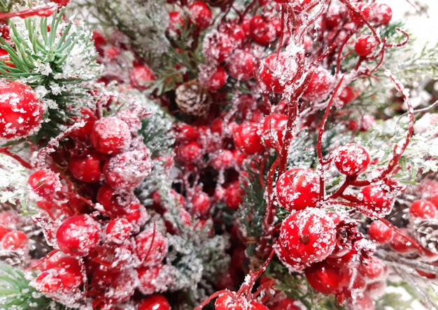 Schöne dekorative Weihnachts- und Frohes neues Jahr-Komposition aus Kiefernzweig, Tannenzapfen und roten Viburnum-Beeren im Schnee. Glänzender Feierhintergrund